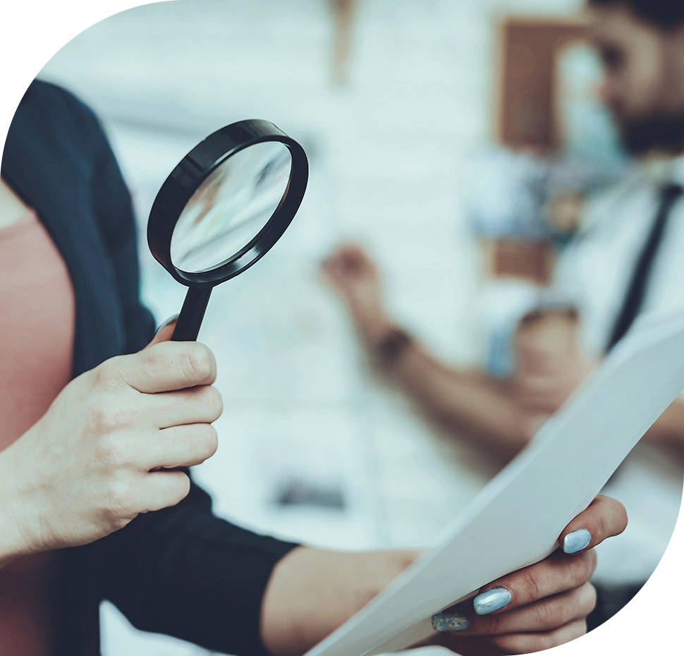 Woman examining document with magnifying glass.