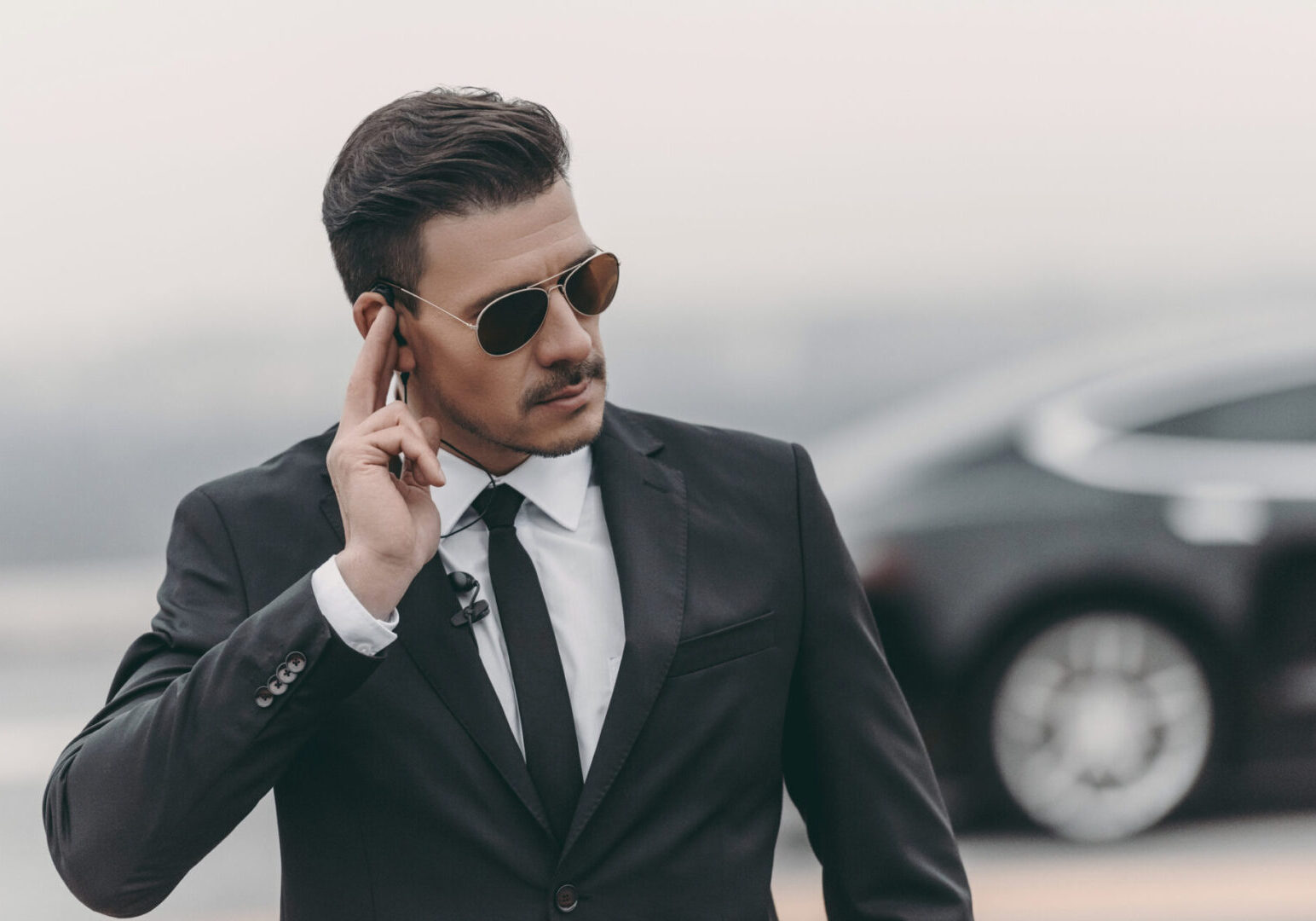 A man in suit and sunglasses talking on his cell phone.